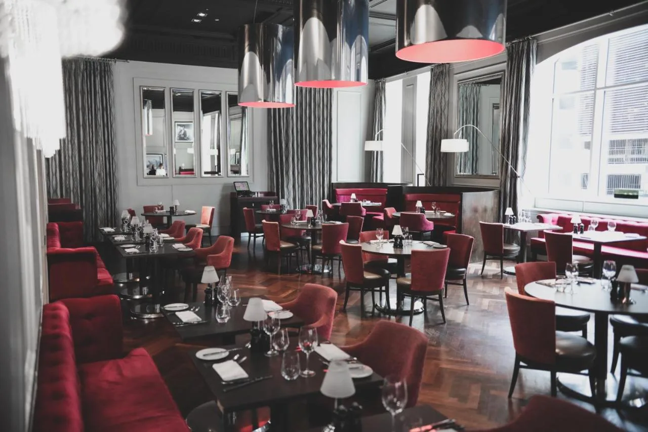 a dining room with tables and red chairs at Hotel Indigo Glasgow by IHG in Glasgow